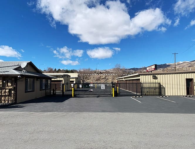 A parking lot with two cars and a fence.